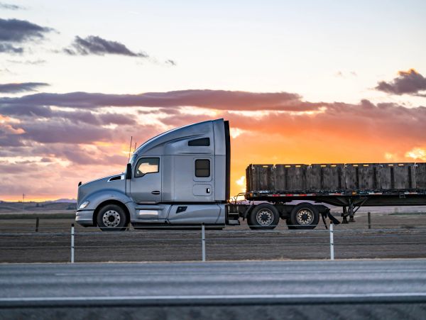 Silver semi-truck parked at sunset.