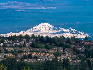 Snow-capped mountain behind a suburban neighborhood under a blue sky.