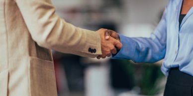 Two people shaking hands in a professional setting.