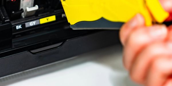 Person replacing yellow ink cartridge in a printer.