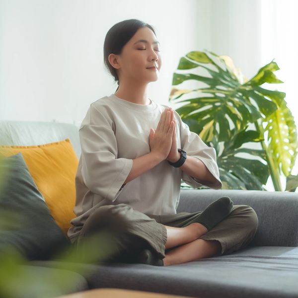 Asian woman sitting on sofa in meditative position