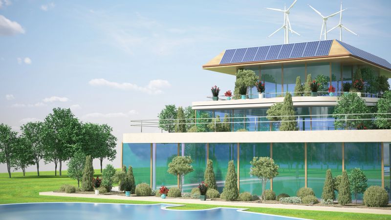 This is a concept of a modern sustainable building with multiple levels, each adorned with greenery and renewable energy sources. The roof is equipped with both solar panels and wind turbines, harnessing natural resources to generate power. The structure is surrounded by a cityscape, suggesting an integration of eco-friendly architecture within an urban environment.