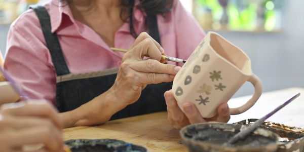 Woman painting a ceramic mug.