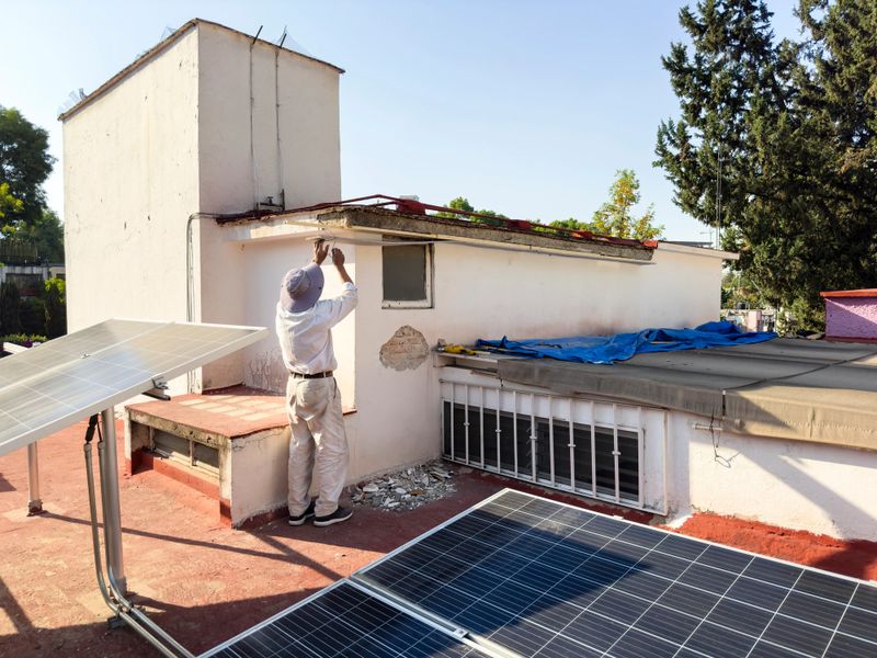 Man working repairing rooftop at Mexico City with solar panels