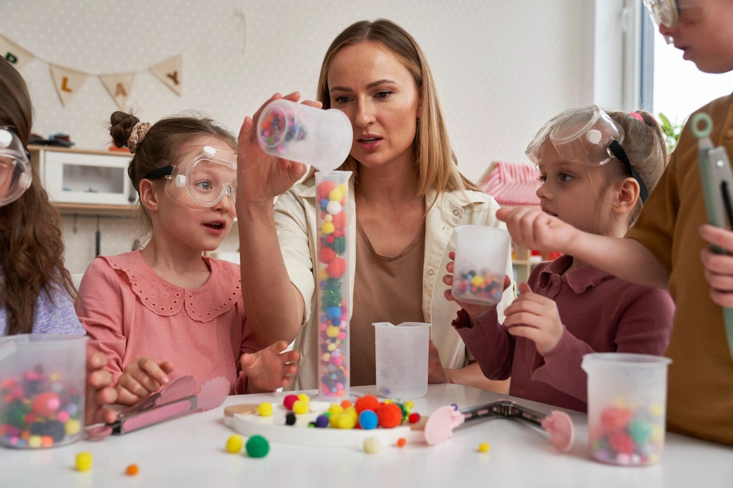 Teacher guiding kids in a colorful science experiment with protective goggles.