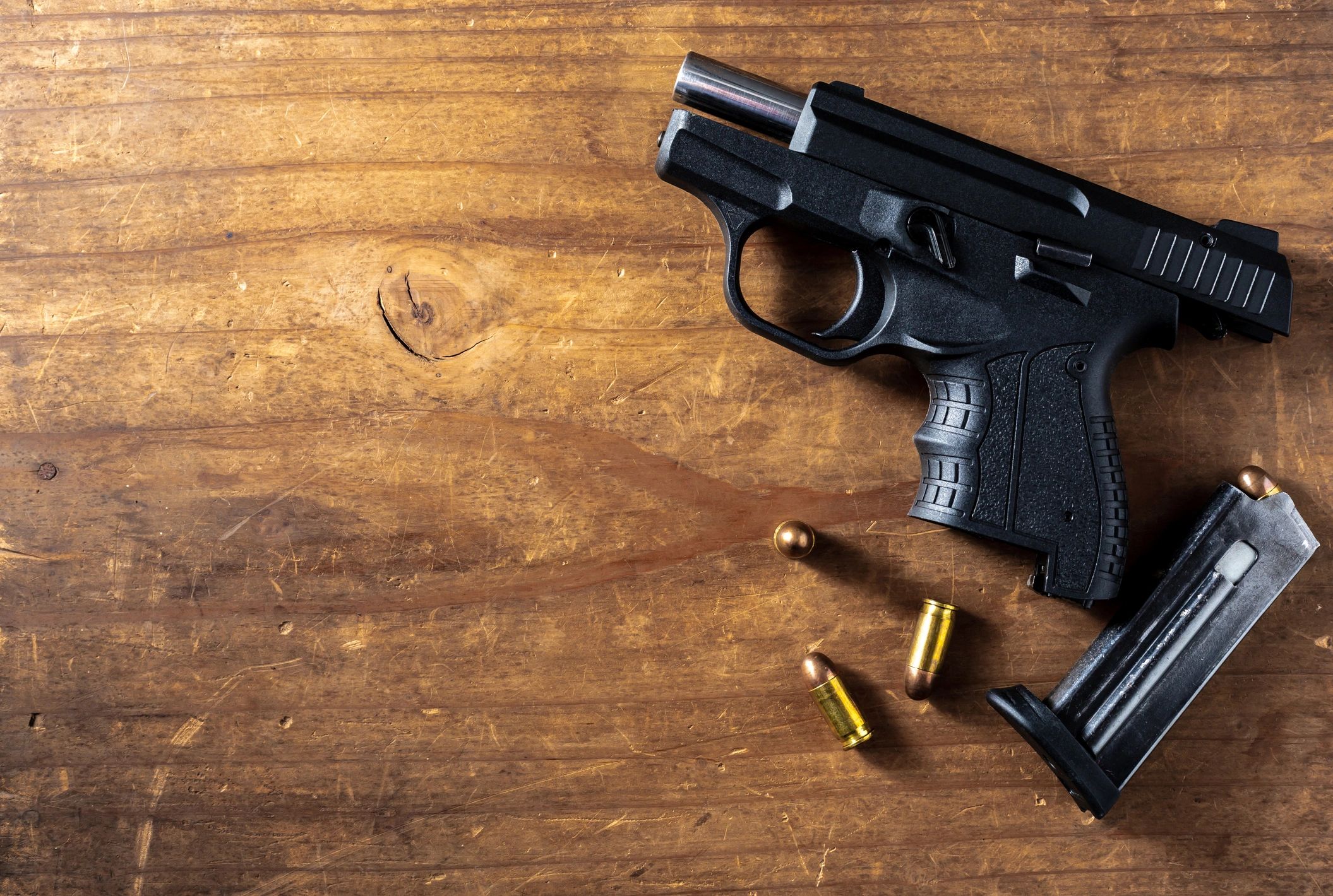 Black semi-automatic pistol with bullets on wooden surface.