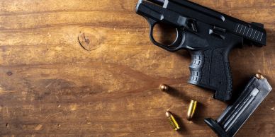 Black pistol with bullets and a magazine on wooden surface.