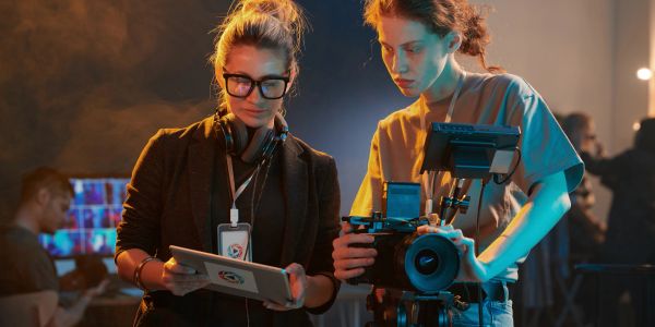 Two women working on a film set with camera and tablet.
