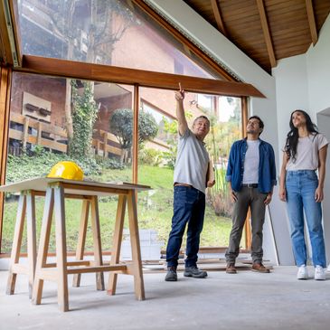 Three people inspecting a room with large windows and wooden ceiling.