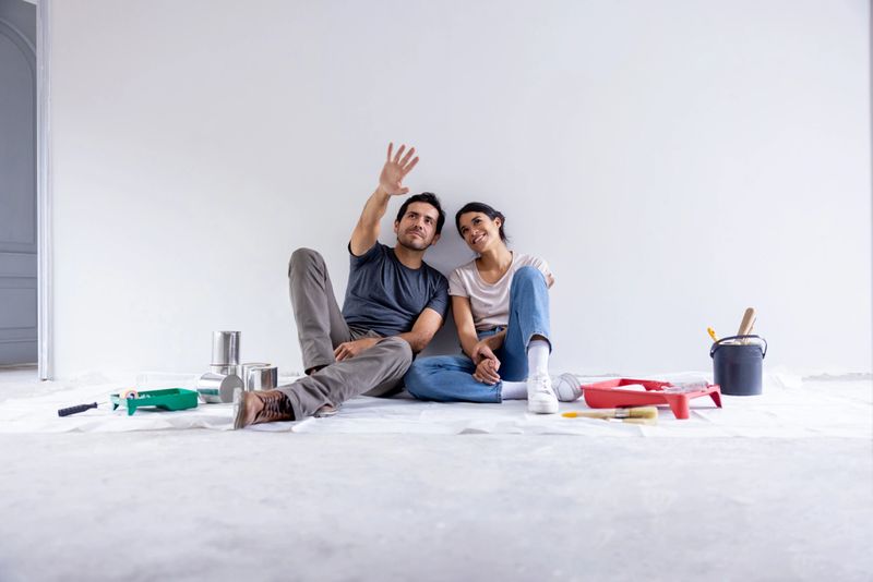 Couple taking a break from painting their house and sitting on the floor sharing ideas and day dreaming