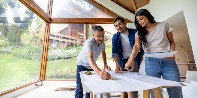 Three people discussing architectural plans at a table.