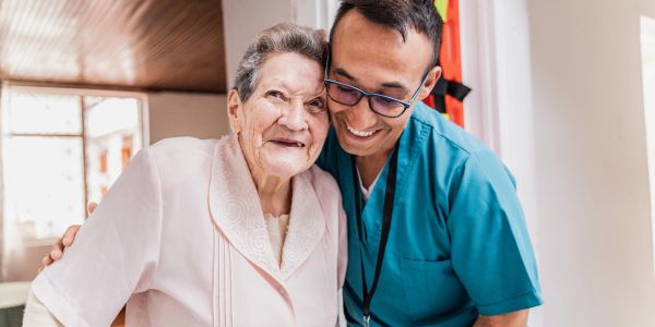 Elderly woman and nurse smiling together.