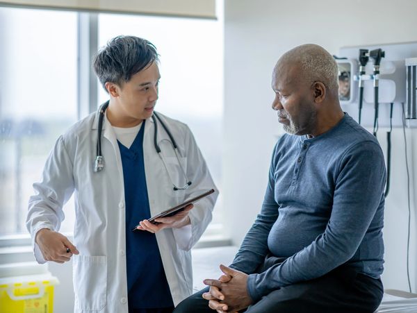 Doctor consulting an older male patient in a medical office.
