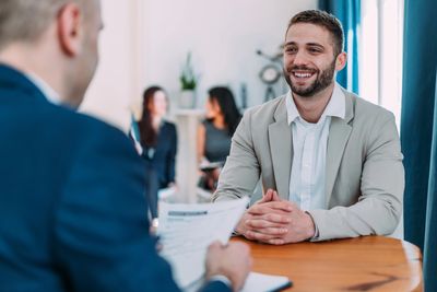 Smiling man in a beige blazer during a job interview.