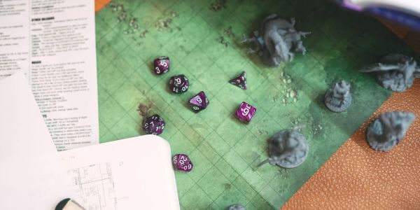 Purple polyhedral dice and miniatures on a green grid game map.