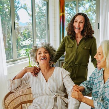 Three women laughing and enjoying each other's company indoors.