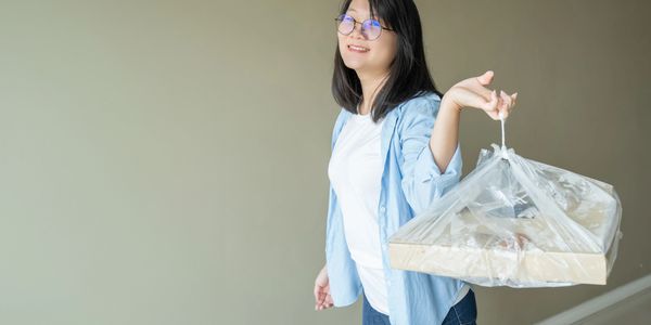 Smiling woman holding a plastic bag with food containers.