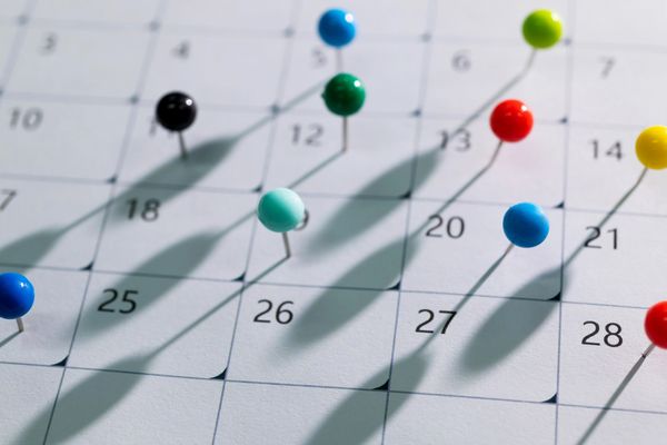 Colorful pushpins marking important dates on a calendar.