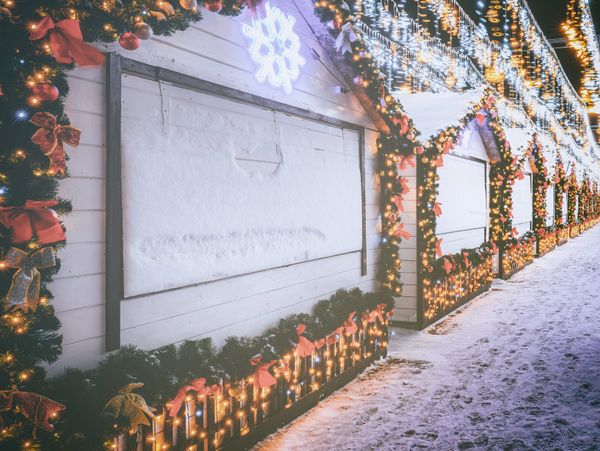 Snow-covered Christmas market stalls adorned with festive lights and decorations.