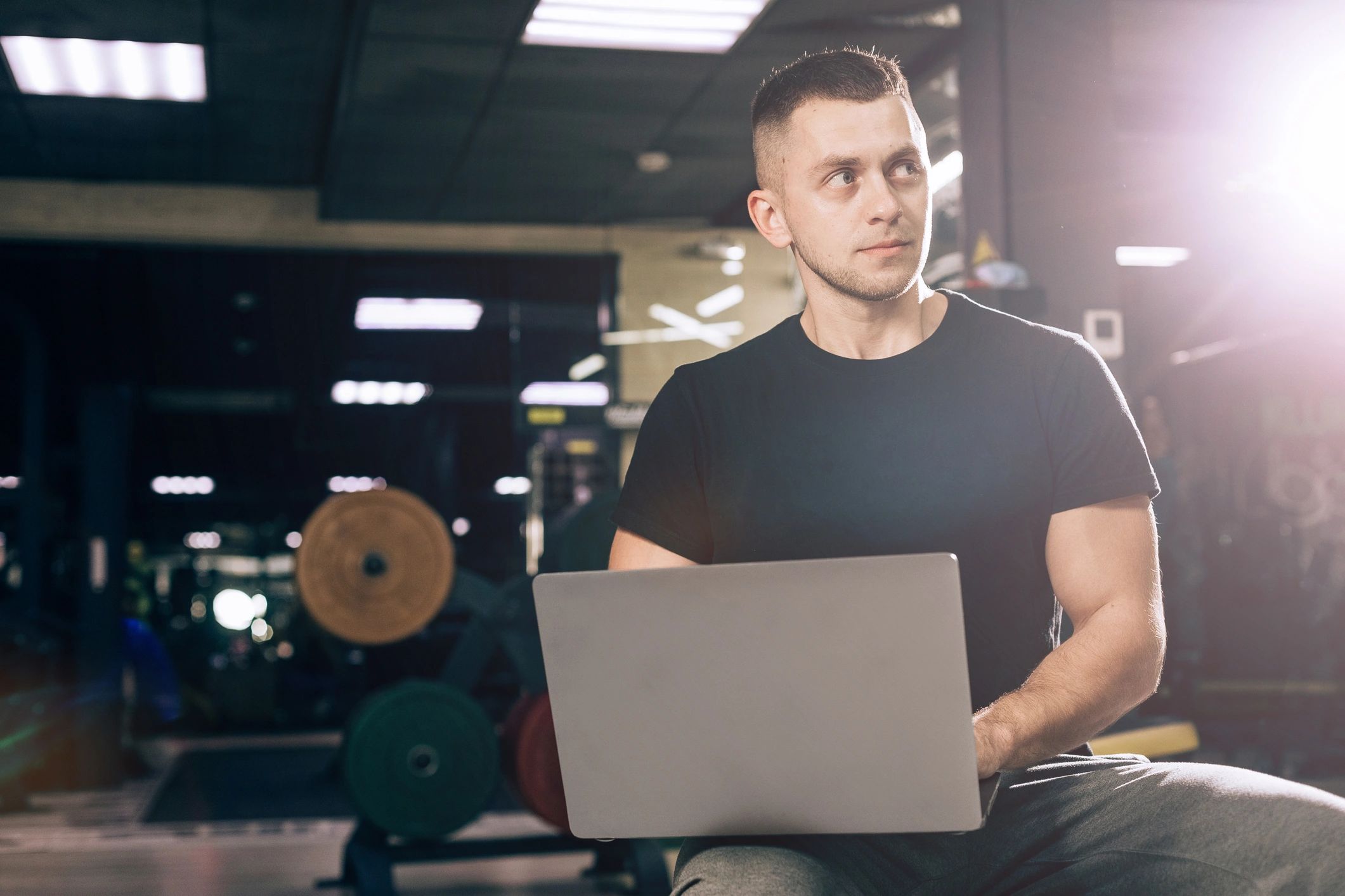Fitness business owner using a laptop in a gym weight room