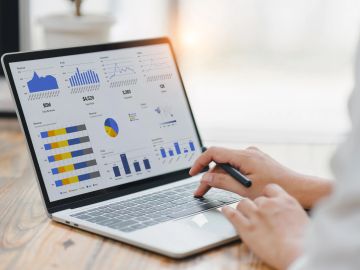 Person analyzing data charts on a laptop.