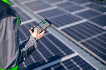 Technician monitoring solar panel performance through a mobile energy management application.