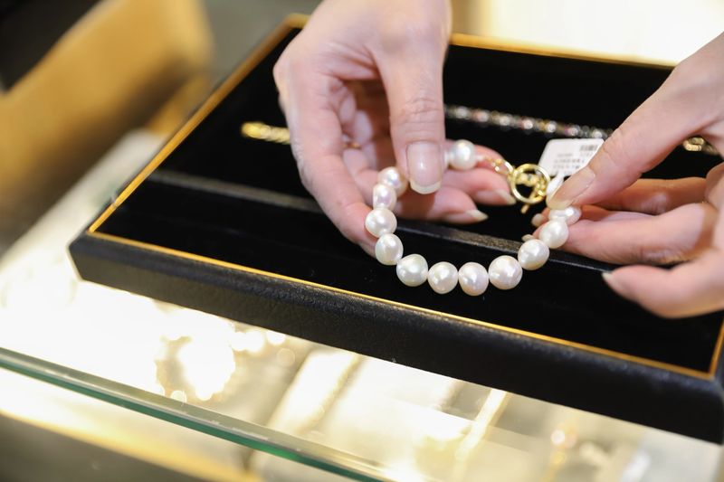 The female clerk in the jewelry store took out the jewelry on the counter and prepared to introduce it to the customers. There were diamond rings, pearl bracelets, jade pendants, etc., all kinds of high-end accessories on the counter.
