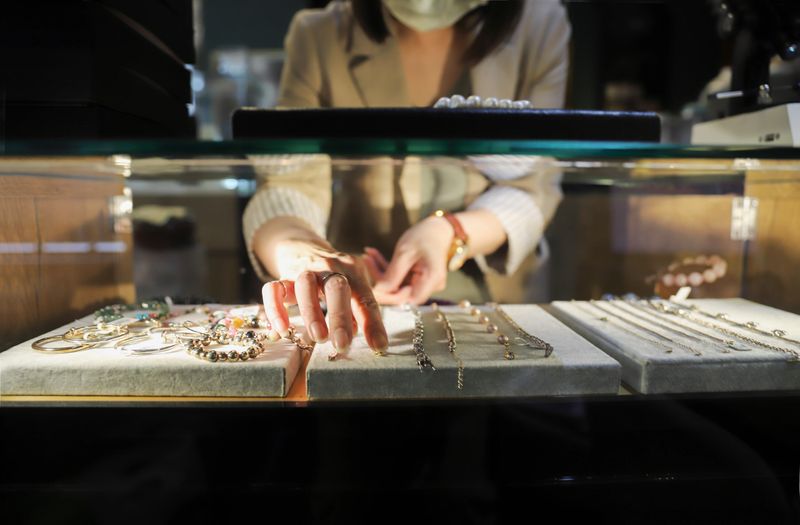 The female clerk in the jewelry store took out the jewelry on the counter and prepared to introduce it to the customers. There were diamond rings, pearl bracelets, jade pendants, etc., all kinds of high-end accessories on the counter.