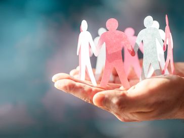 Paper cutout figures held in a hand symbolizing unity.