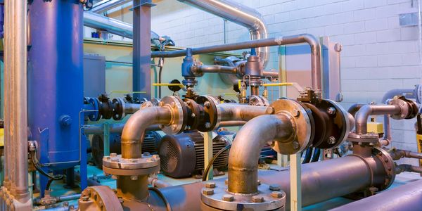 Industrial pipes and machinery in a mechanical room.