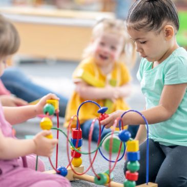 Children playing with bead maze toy indoors.