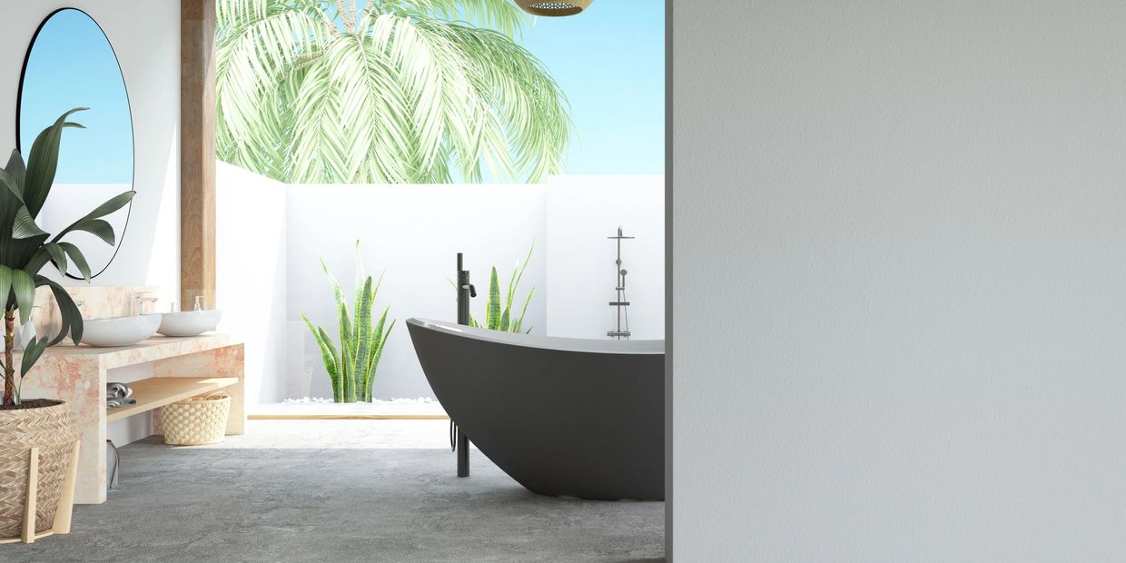 Modern bathroom with black bathtub and outdoor plants.