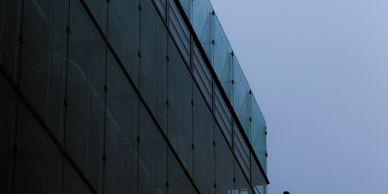 Workers cleaning glass panels on a building facade using a lift.
