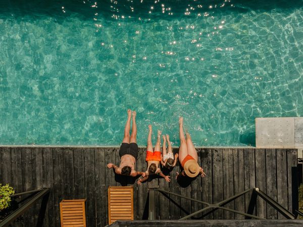 Family enjoying a sunny day by the pool, dipping their feet in the water.