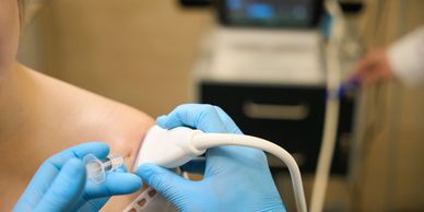 Medical professional performing an ultrasound-guided injection on a patient's shoulder.