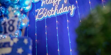 Blue-themed 18th birthday party decorations with balloons and lights.
