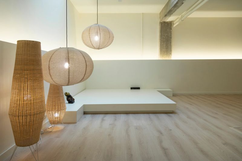 Contemporary meditation area lit by stylish lamps, with minimalist decor and a wooden floor, fostering tranquility.