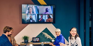 Team in a meeting room on a video call with colleagues in another country