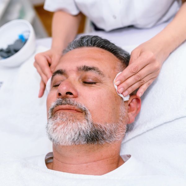 Man receiving facial treatment with eyes closed.