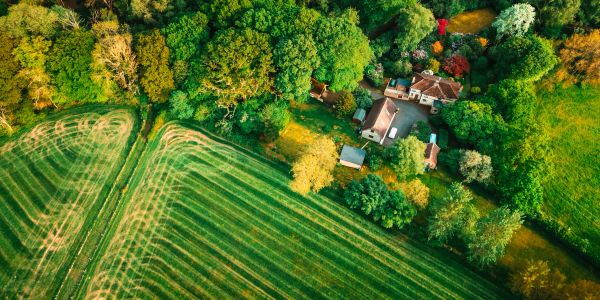 Aerial view of a house surrounded by trees and farmland.
