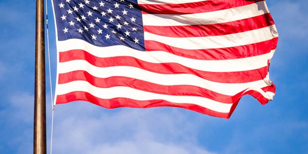 American flag waving against a clear blue sky.