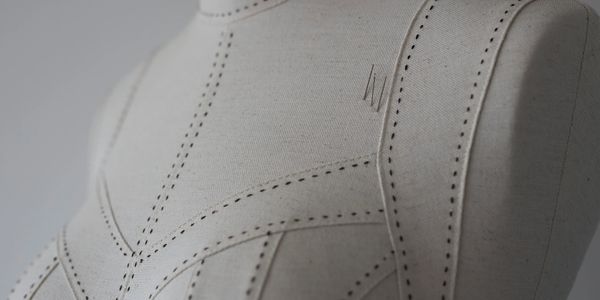 Close-up of a tailor's mannequin with marked sewing lines and pins.