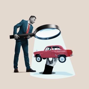 Man in suit examines a small red car held by a hand using a giant magnifying glass.