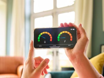 Person holding phone with energy meters displayed