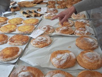 Various pastries displayed on trays with a hand pointing at one.