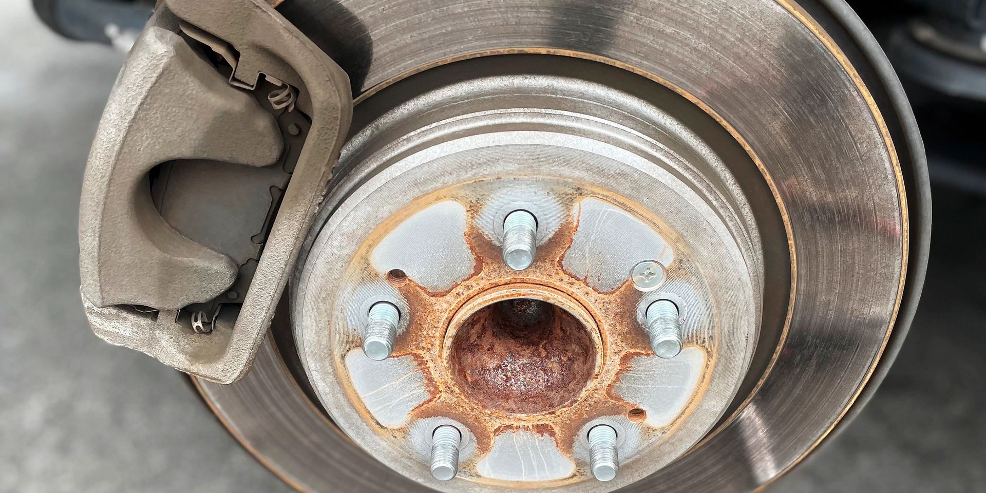 Mobile brake repair showing worn rotor and caliper during on-site service in Indiana