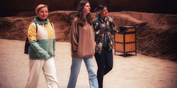 Three women walking and exploring a rocky cave area together.