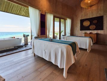 Spa room with massage tables and ocean view balcony.