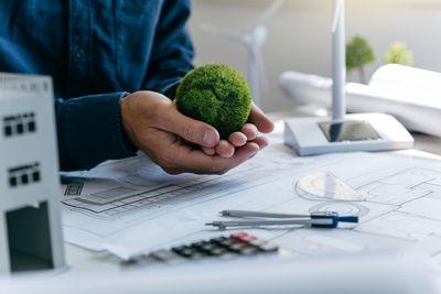 Hands with moss ball over blueprints.