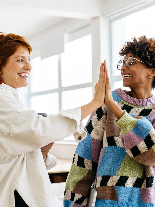 Two women, one facing the other, smiling and high fiving. Optimizing Her2